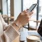 Person using a smartphone with a blurred cafe background