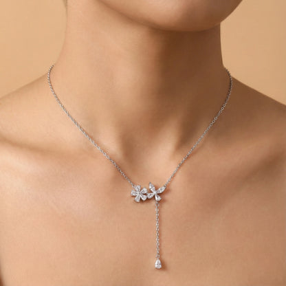 Silver necklace with floral pendant on a person against a beige background