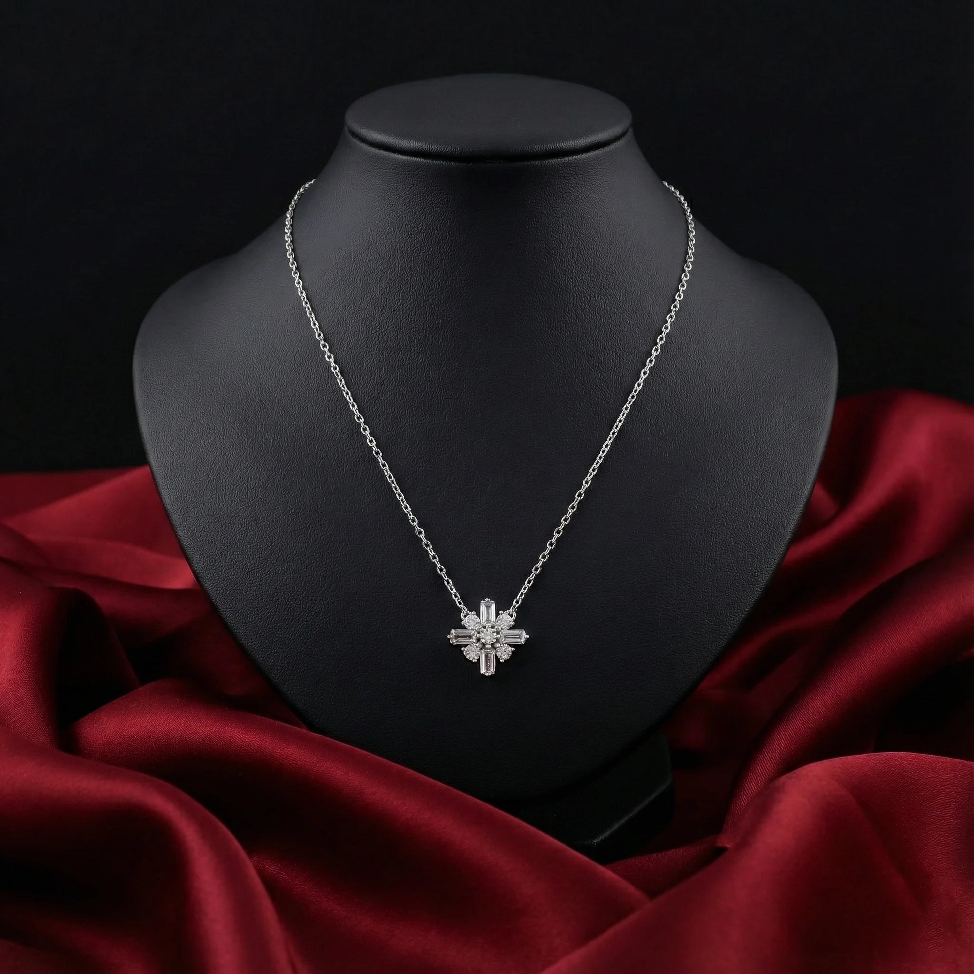 Silver necklace with a star-shaped pendant on a black mannequin bust against a red fabric background