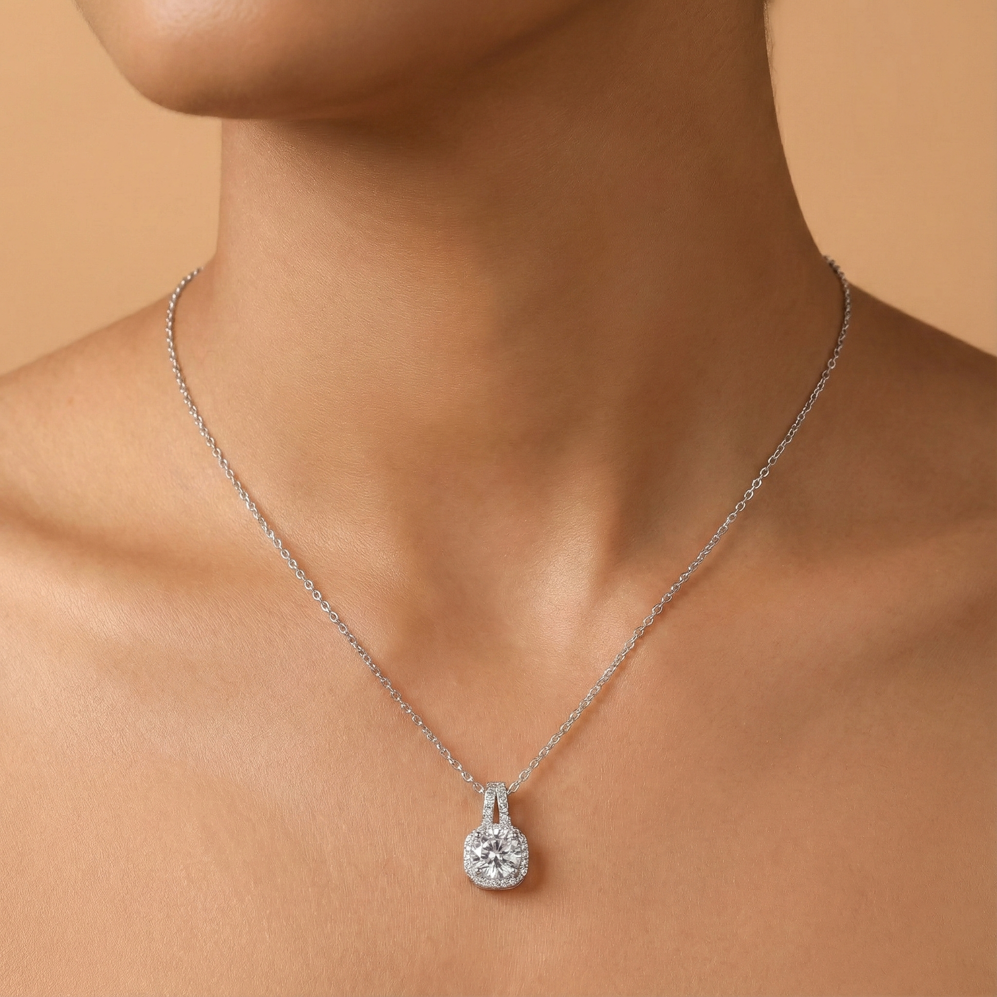 Silver necklace with a diamond pendant on a person's neck against a beige background