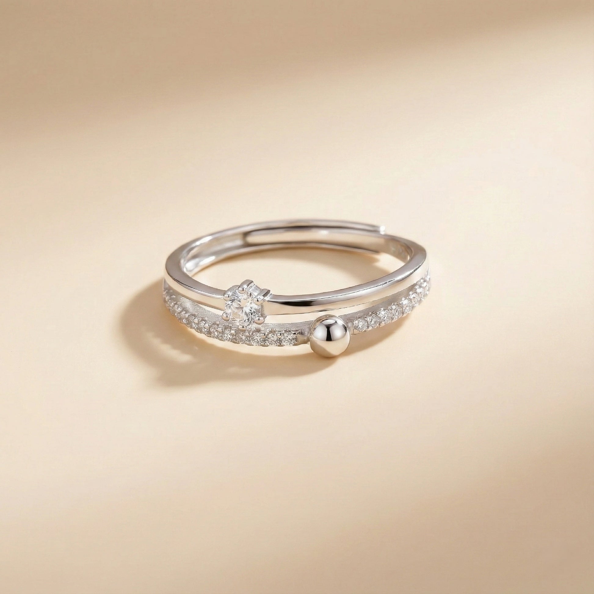 Silver ring with a small ball on a beige background