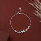 Silver bracelet with floral and bow charms on a brown background