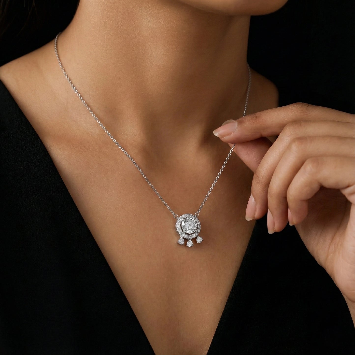 Silver necklace with a pendant worn by a person against a black background