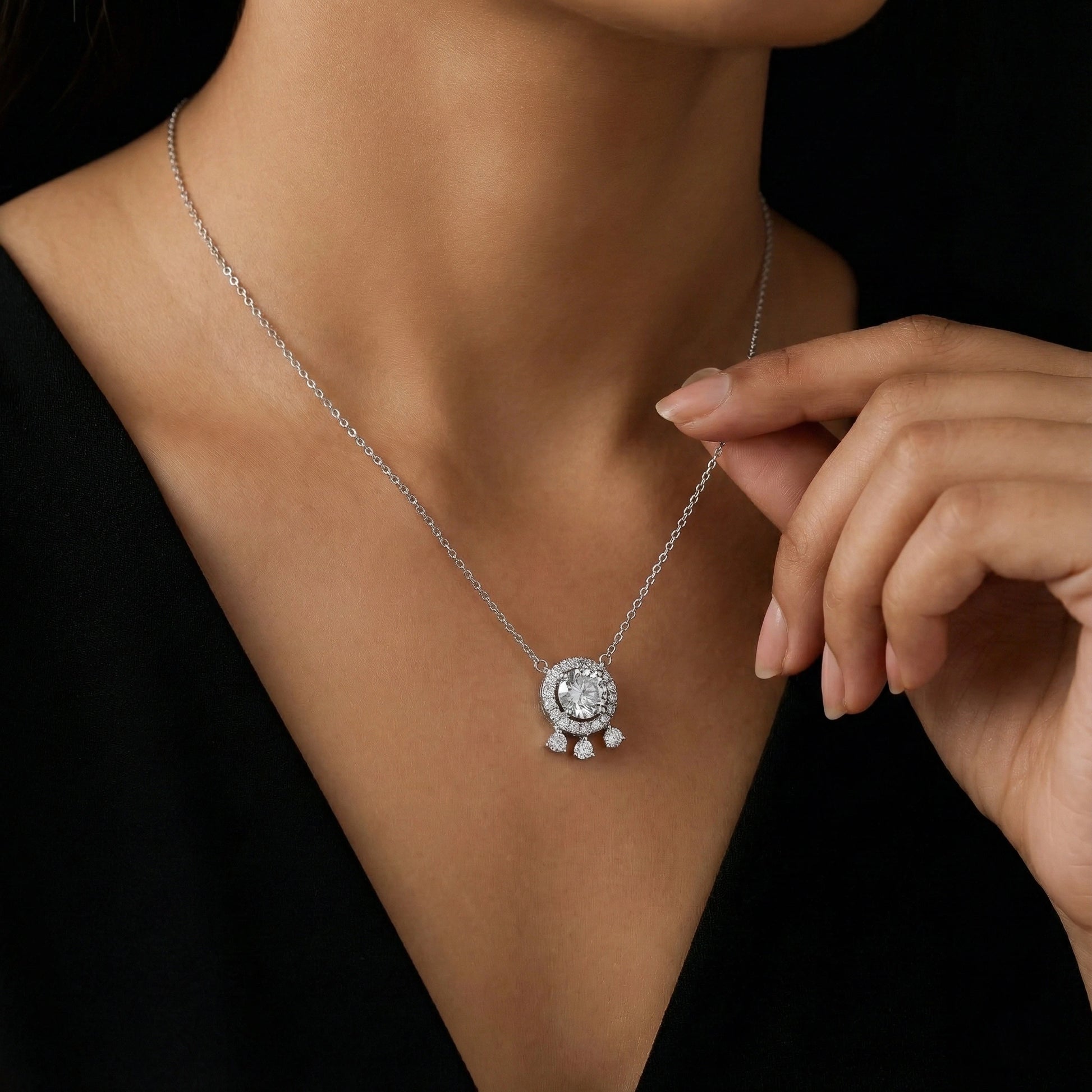 Silver necklace with a pendant worn by a person against a black background