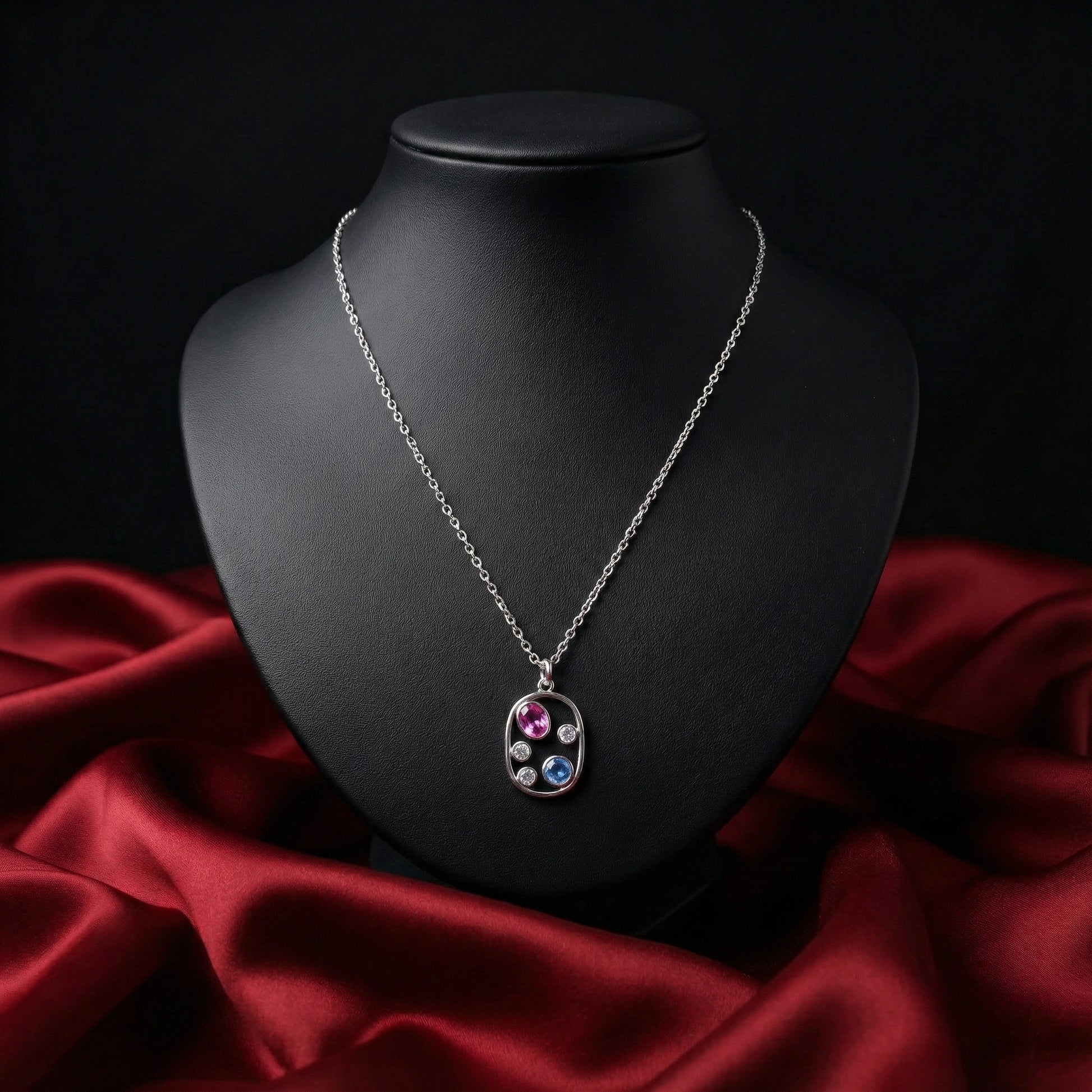 Silver necklace with a multicolored pendant on a black mannequin bust against a red fabric background