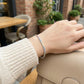 Hand wearing a colorful beaded bracelet with a blurred outdoor cafe background