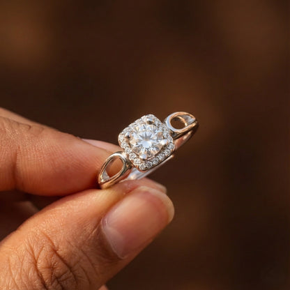 Rose gold ring with a diamond held by a hand against a blurred brown background