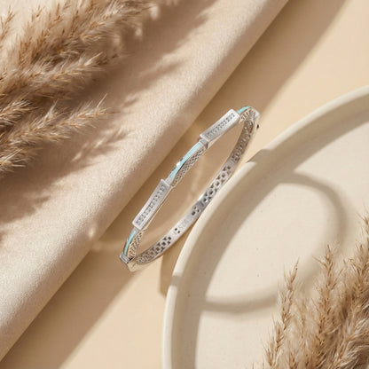 Silver bracelet with blue accents on a beige fabric background with dried grasses.