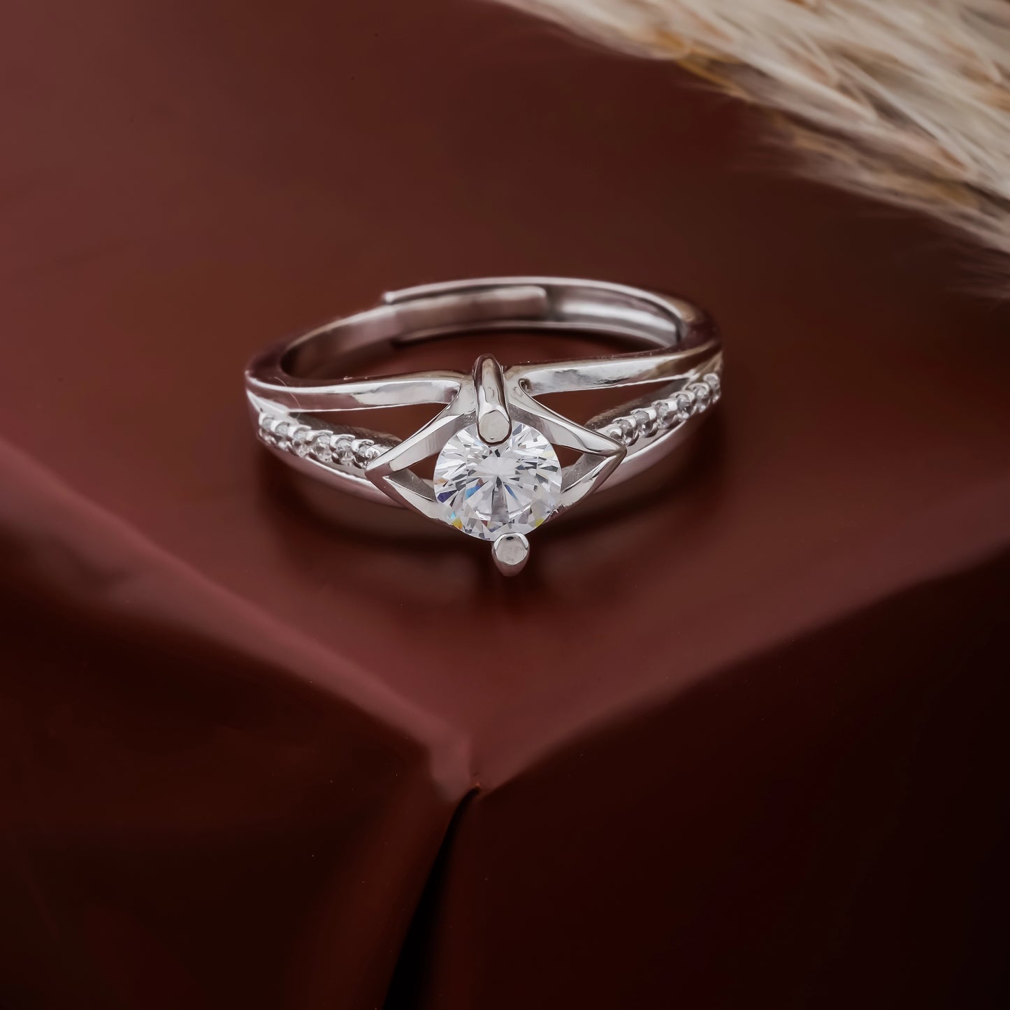 Silver ring with a diamond on a brown fabric background