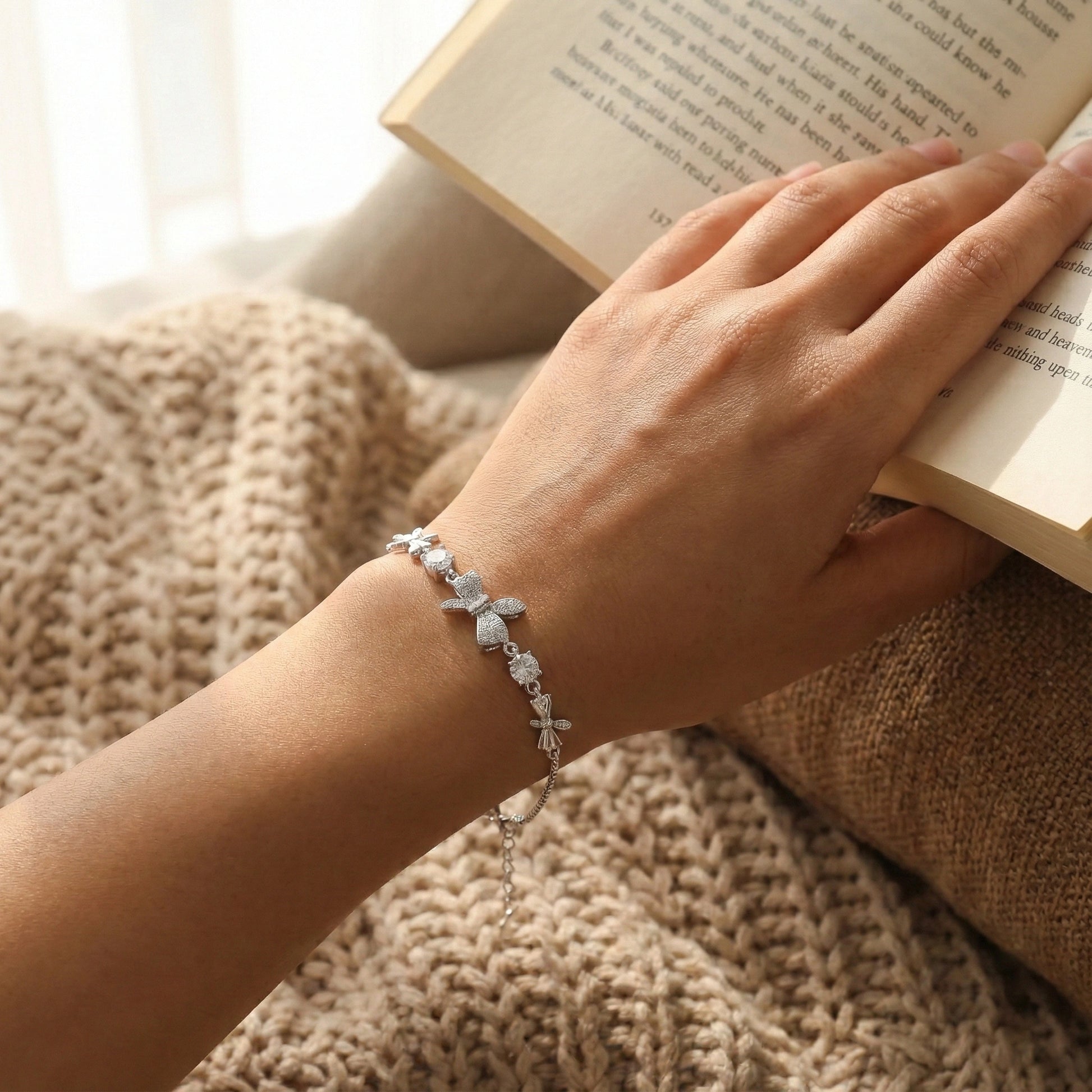 Hand wearing a bracelet holding an open book on a textured surface
