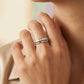 Close-up of a hand wearing two silver rings on a neutral background