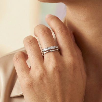 Close-up of a hand wearing two silver rings on a neutral background