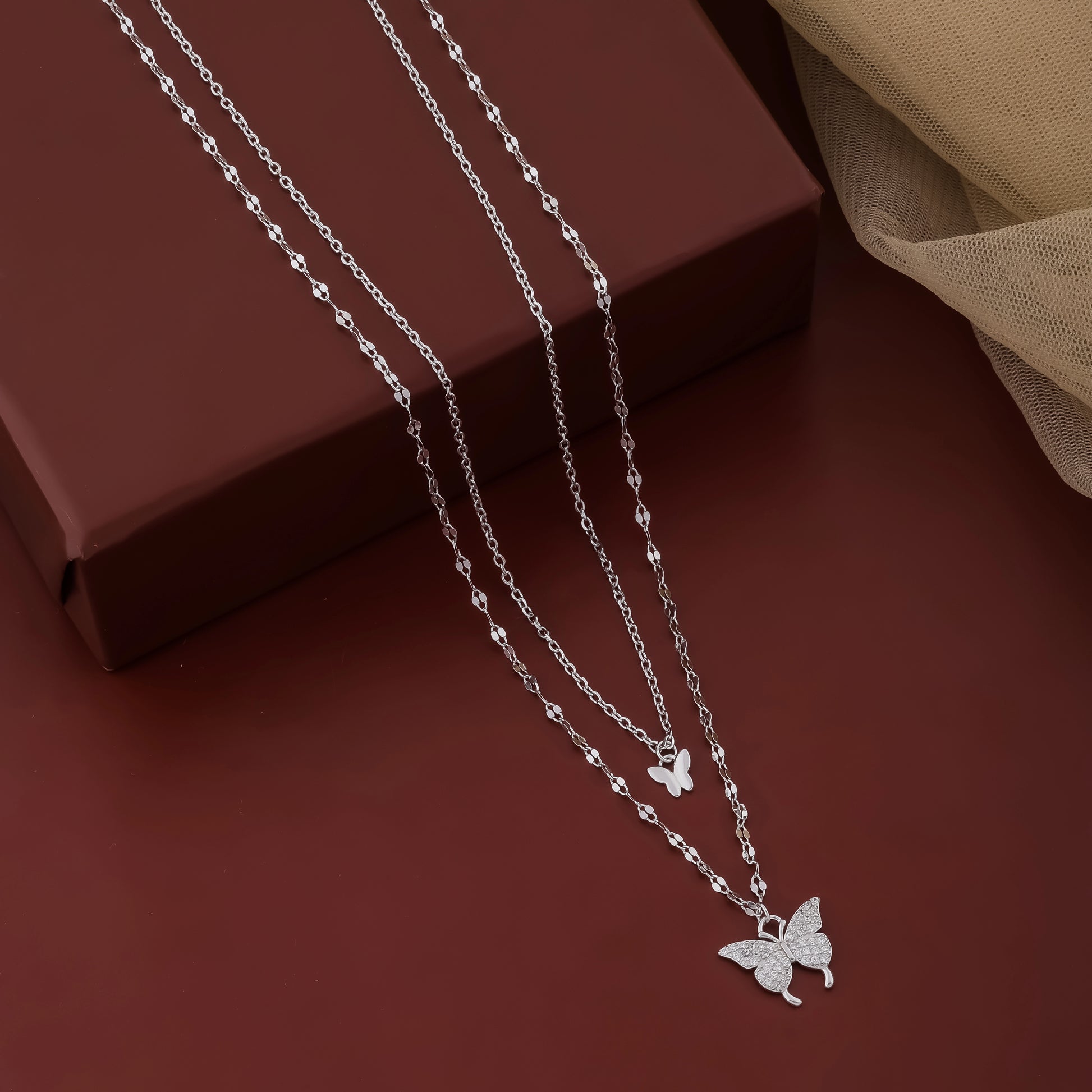Silver butterfly necklace on a brown surface