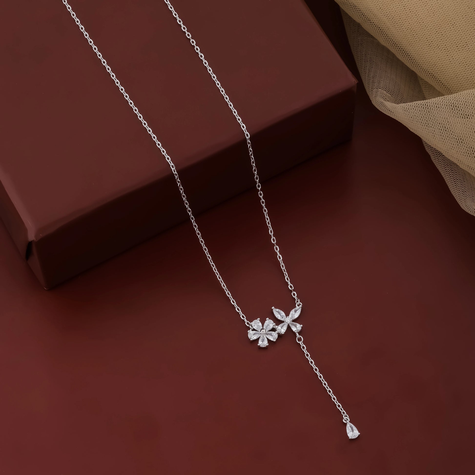 Silver necklace with a clover pendant on a brown surface