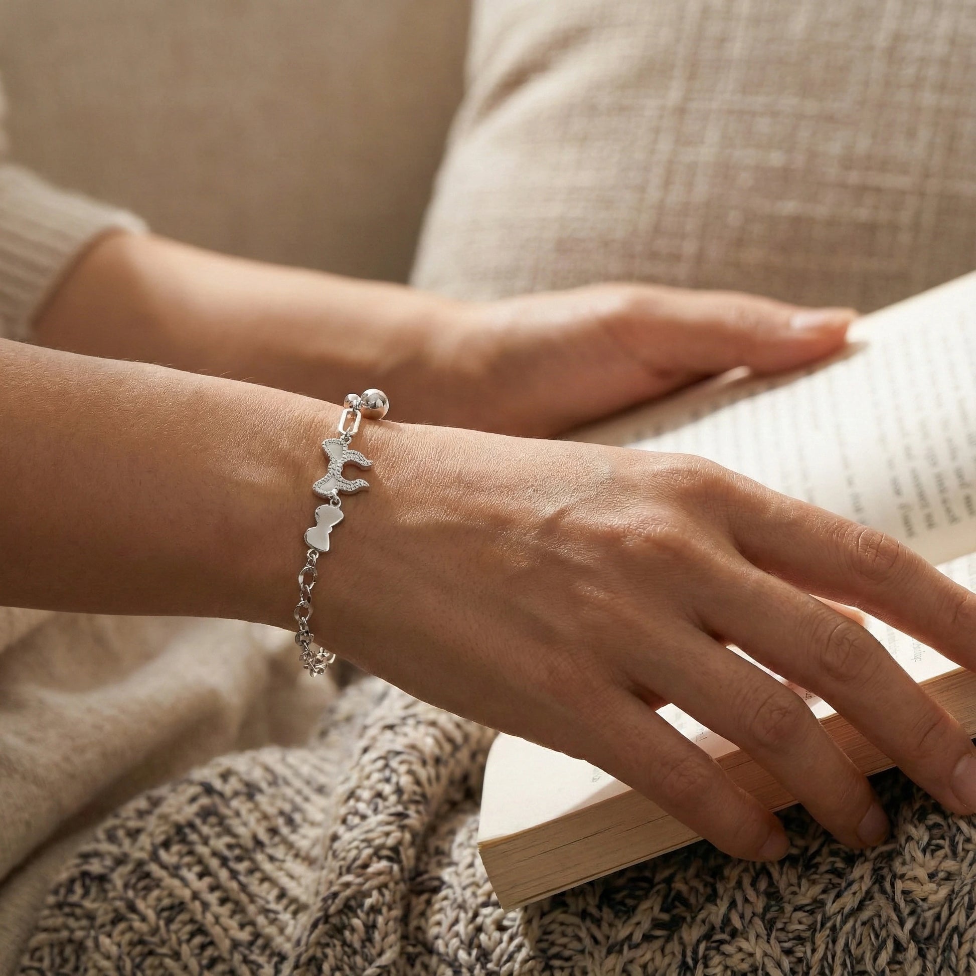 Person wearing a silver bracelet with a book in the background