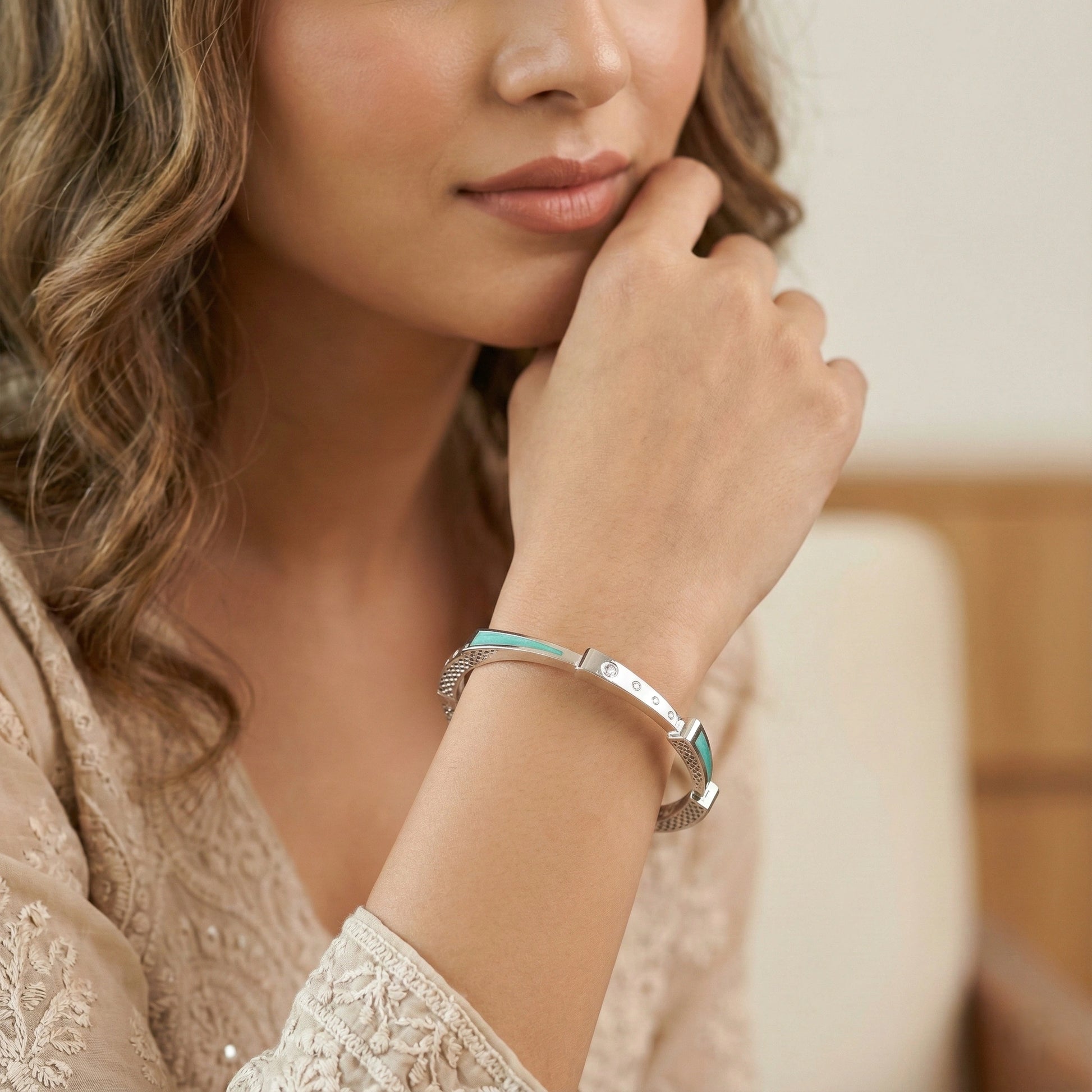 Woman wearing a silver bracelet with a blue accent on her wrist.