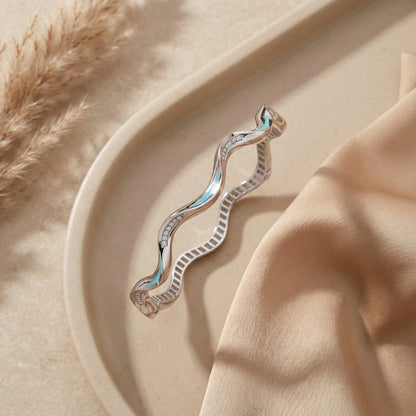 Silver earring on a beige surface with a soft focus background