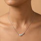 Silver necklace with a leaf-shaped pendant on a person against a beige background