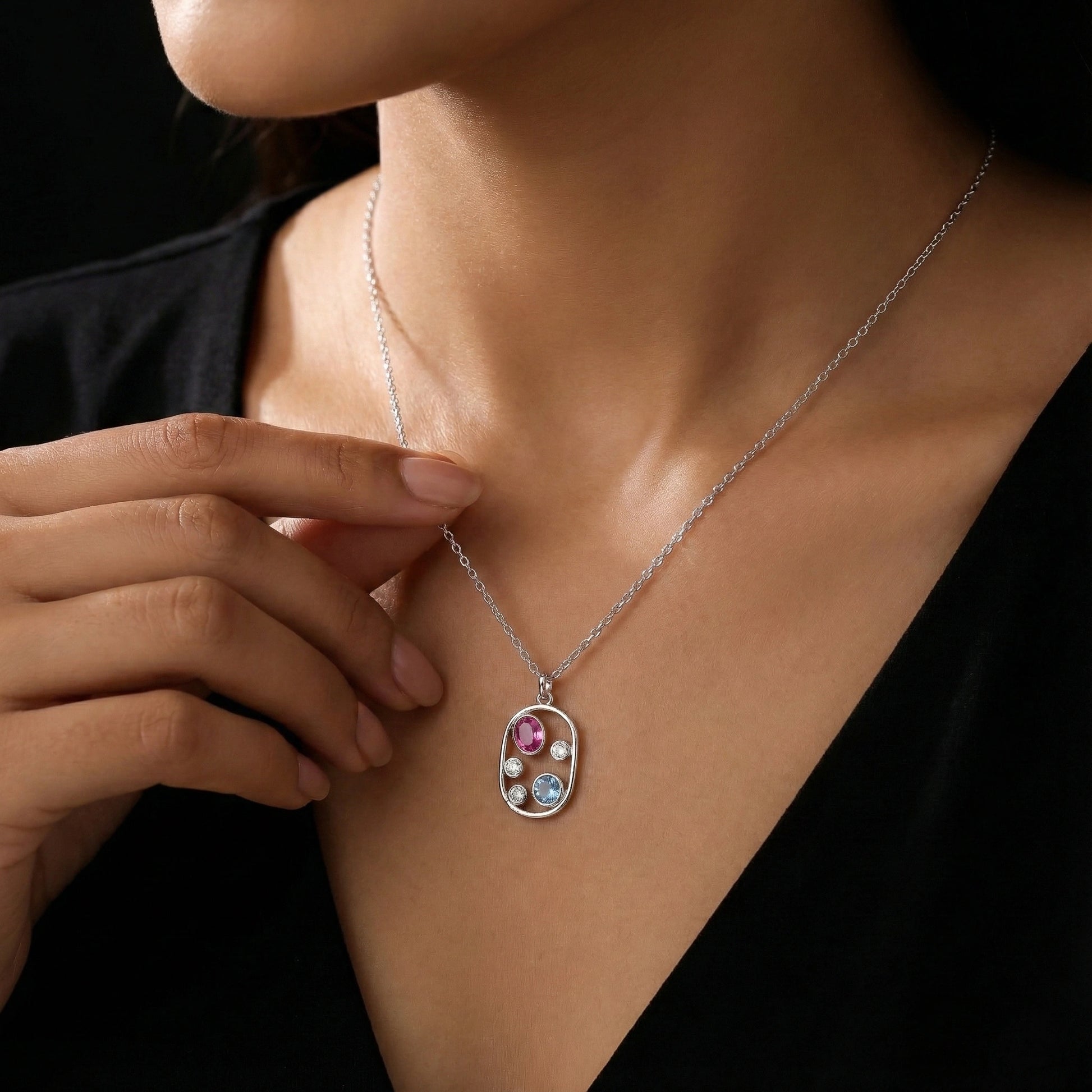 Necklace with a pendant featuring colorful stones worn by a person against a dark background