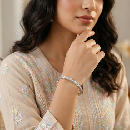 Woman wearing a silver bracelet on her wrist, with a blurred background