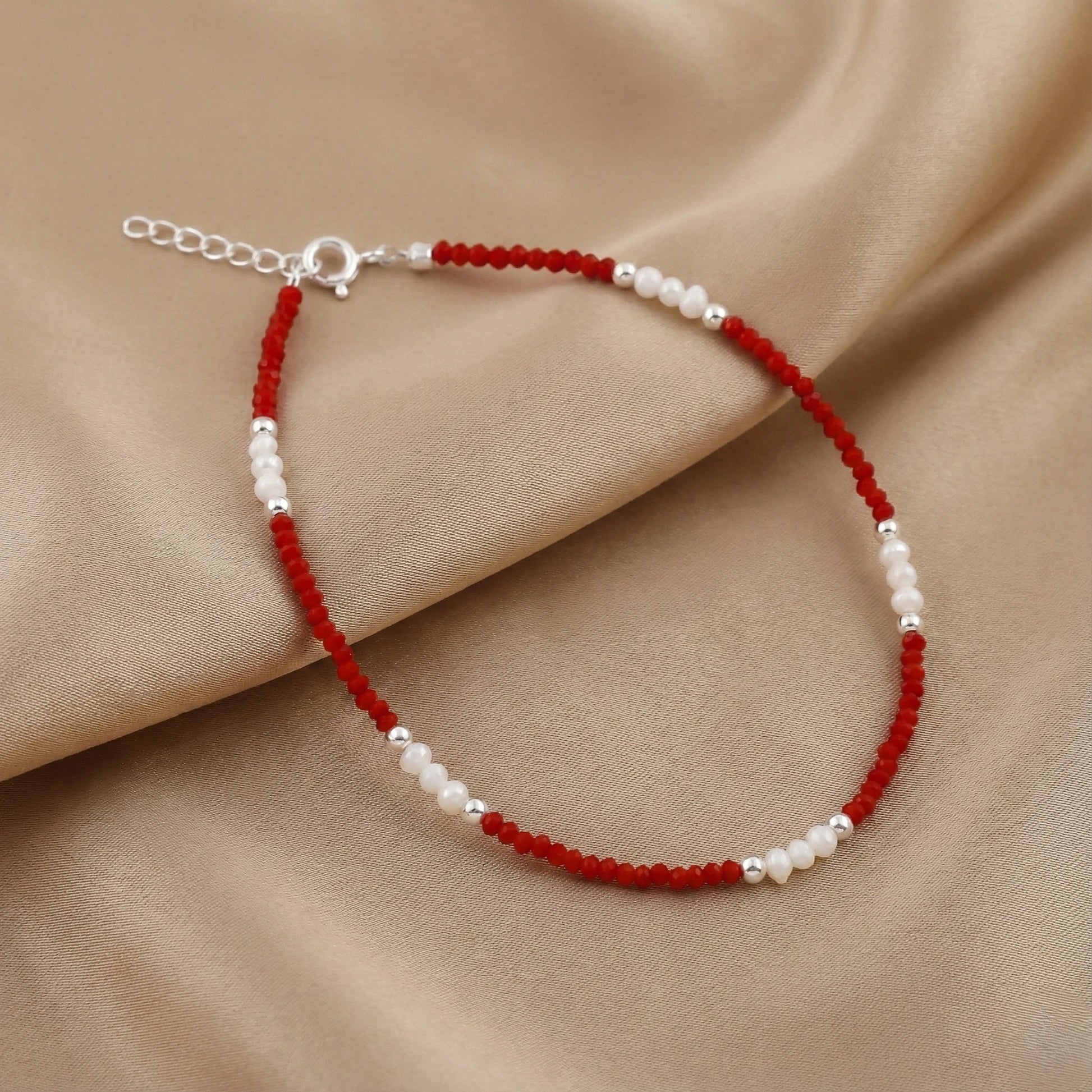 Beaded bracelet with red and white beads on a beige fabric background