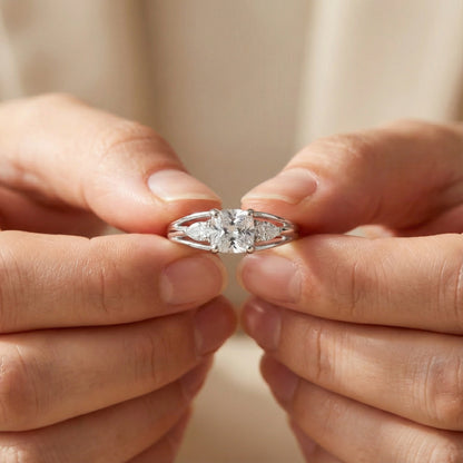 Close-up of hands holding a silver ring with a diamond