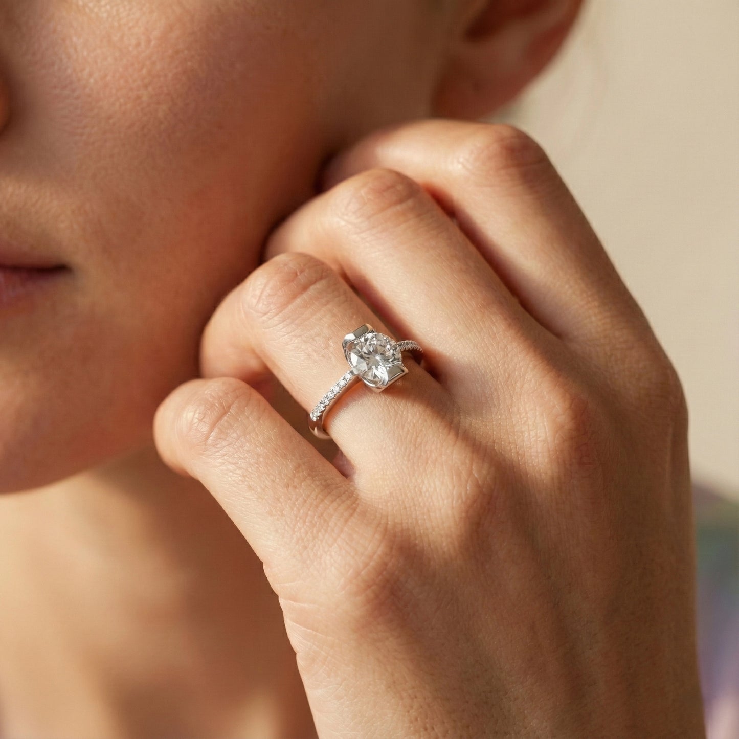 Close-up of a hand wearing a diamond ring with a blurred background
