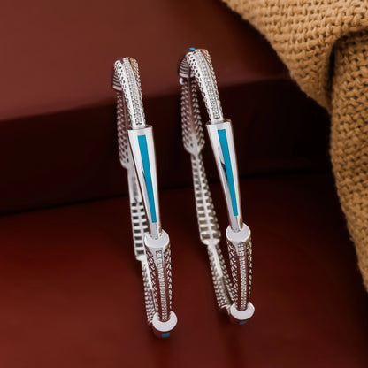 Pair of silver hoop earrings with blue accents on a brown surface