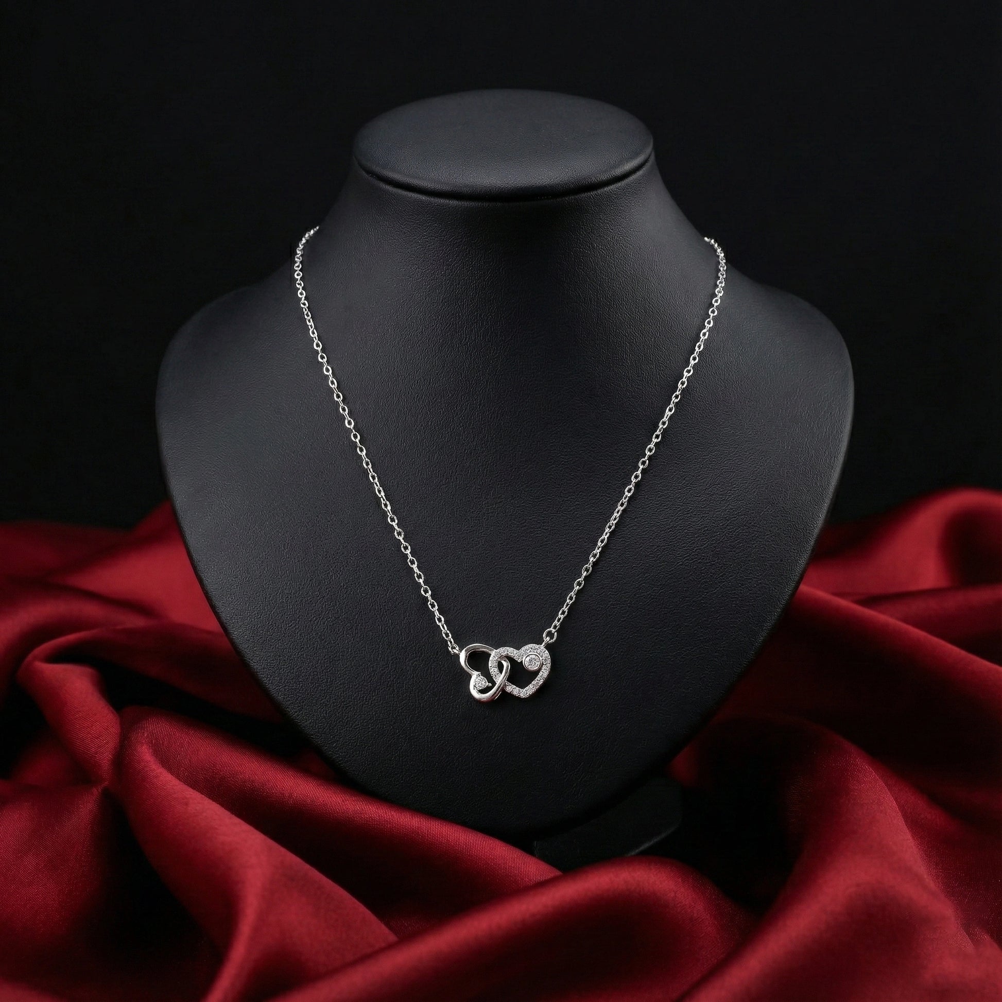 Silver necklace on a black mannequin bust with red fabric underneath