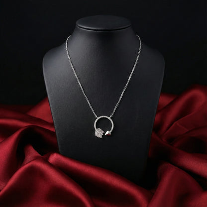Silver necklace with a circular pendant on a black stand against a red fabric background