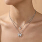 Silver butterfly necklace on a person against a beige background