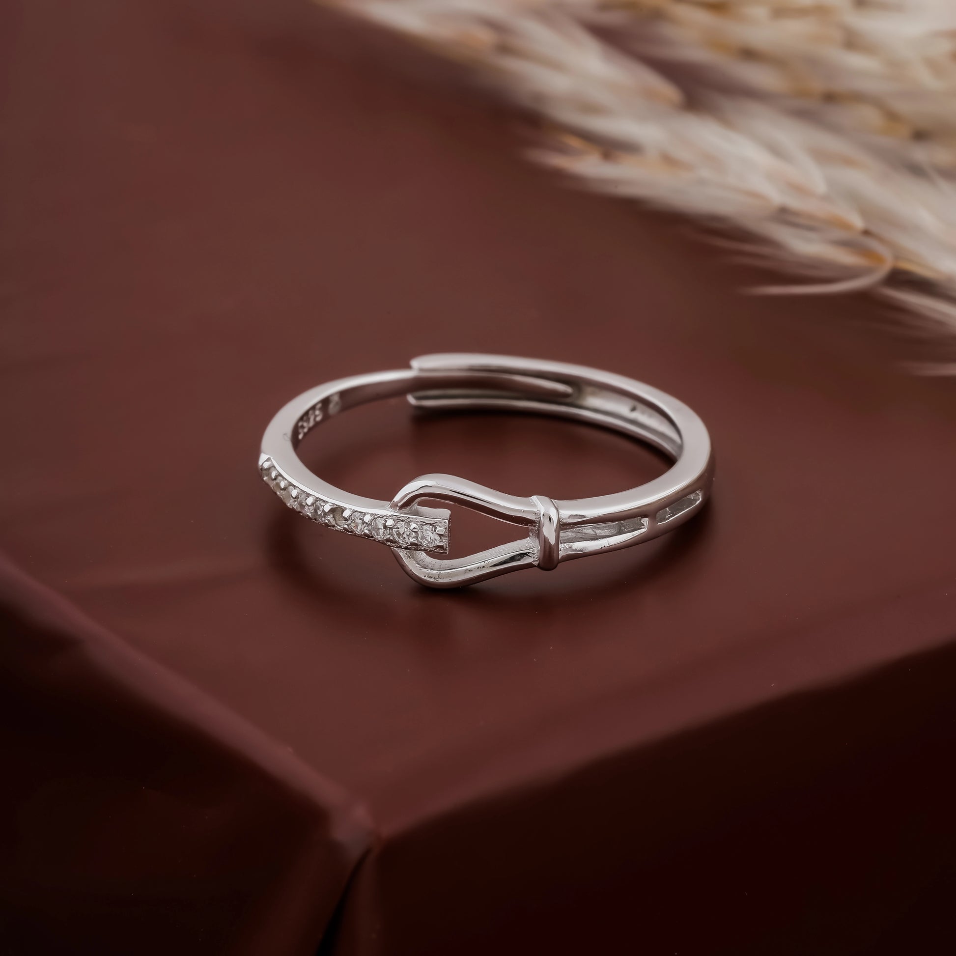 Silver bow-shaped ring on a brown fabric background