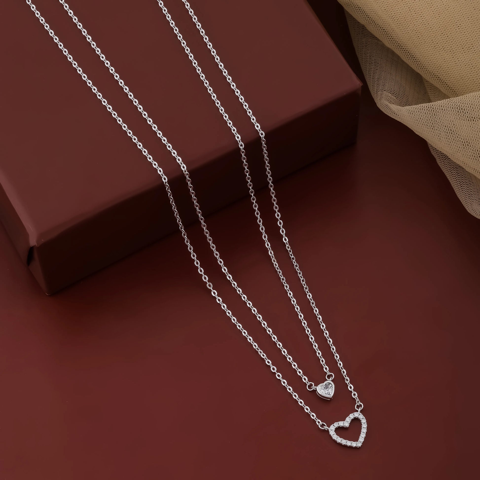 Silver necklace with heart pendants on a brown surface