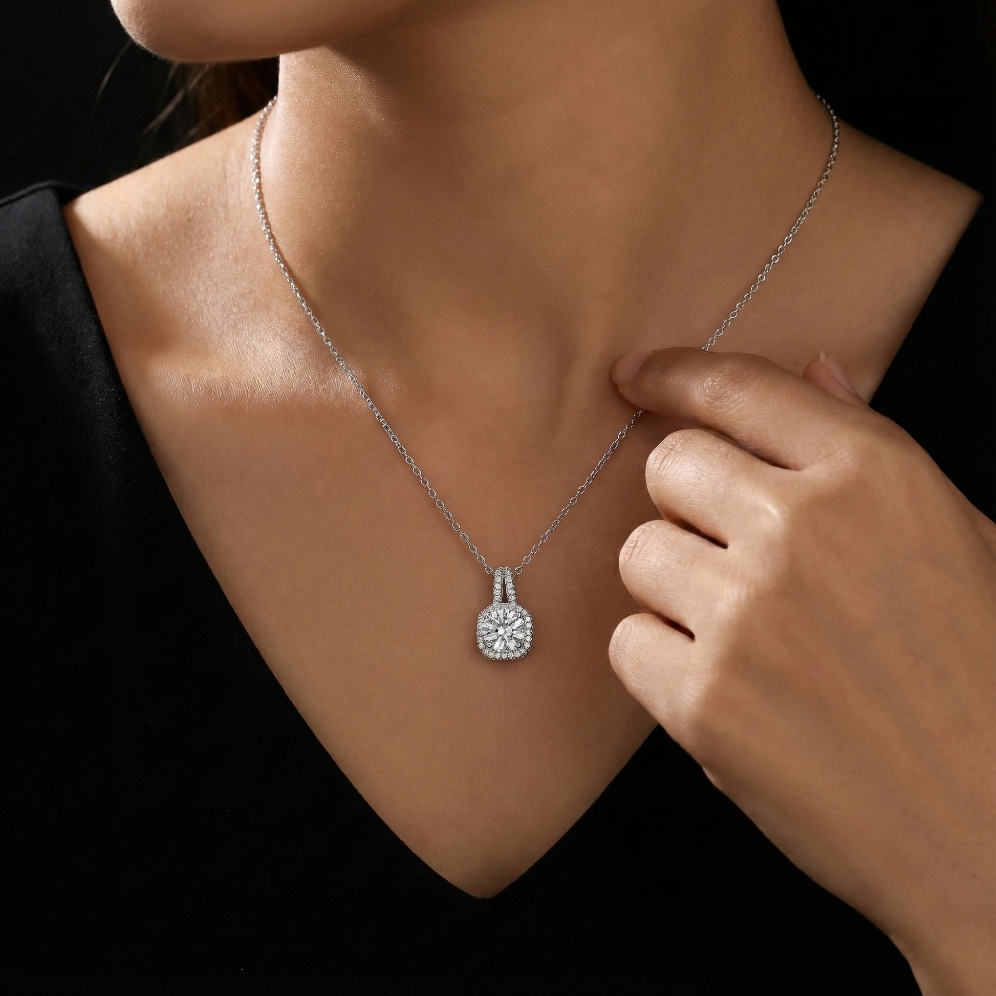 Silver necklace with a pendant worn by a person against a black background