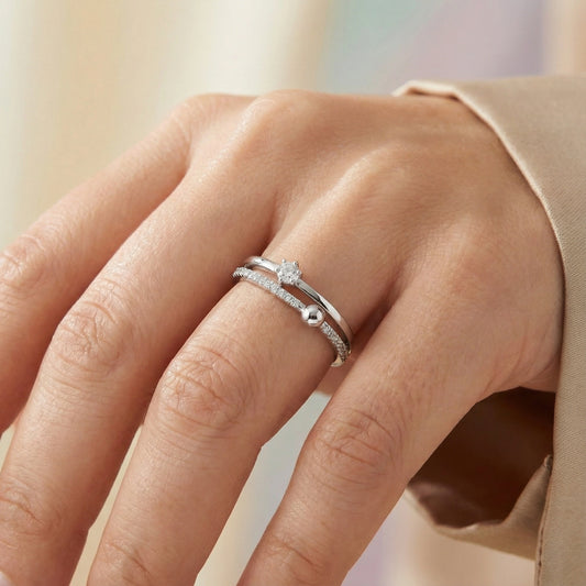 Close-up of a hand wearing two silver rings with a blurred background