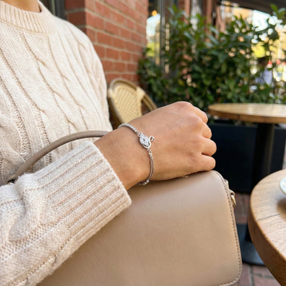Person holding a beige handbag with a blurred outdoor setting