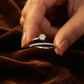 Close-up of a hand holding two diamond rings on a brown fabric background