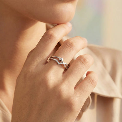 Close-up of a hand wearing a silver ring with a blue gemstone, against a soft blurred background.