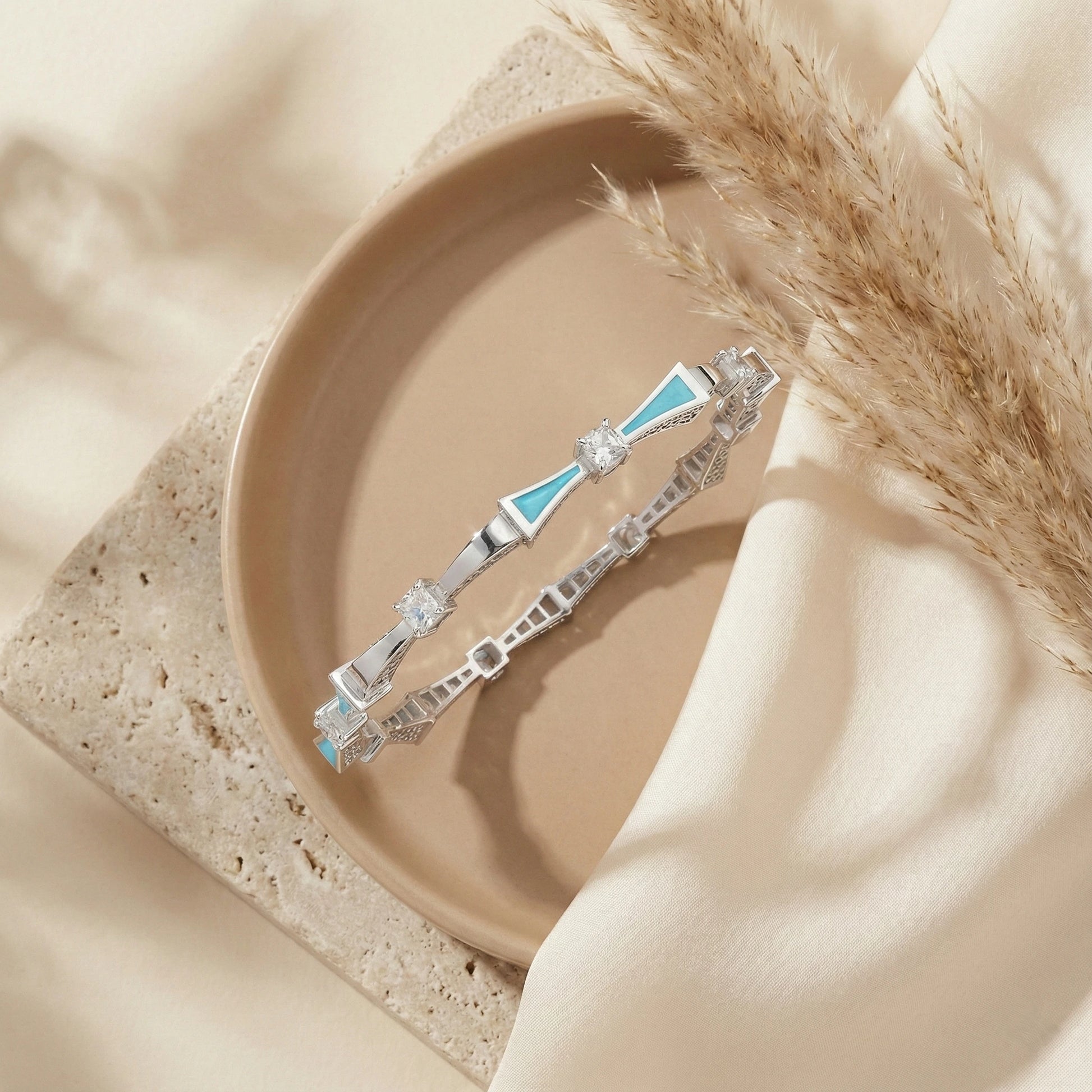 Silver bracelet with blue accents on a beige plate with pampas grass