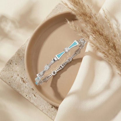 Silver bracelet with blue accents on a beige plate with pampas grass