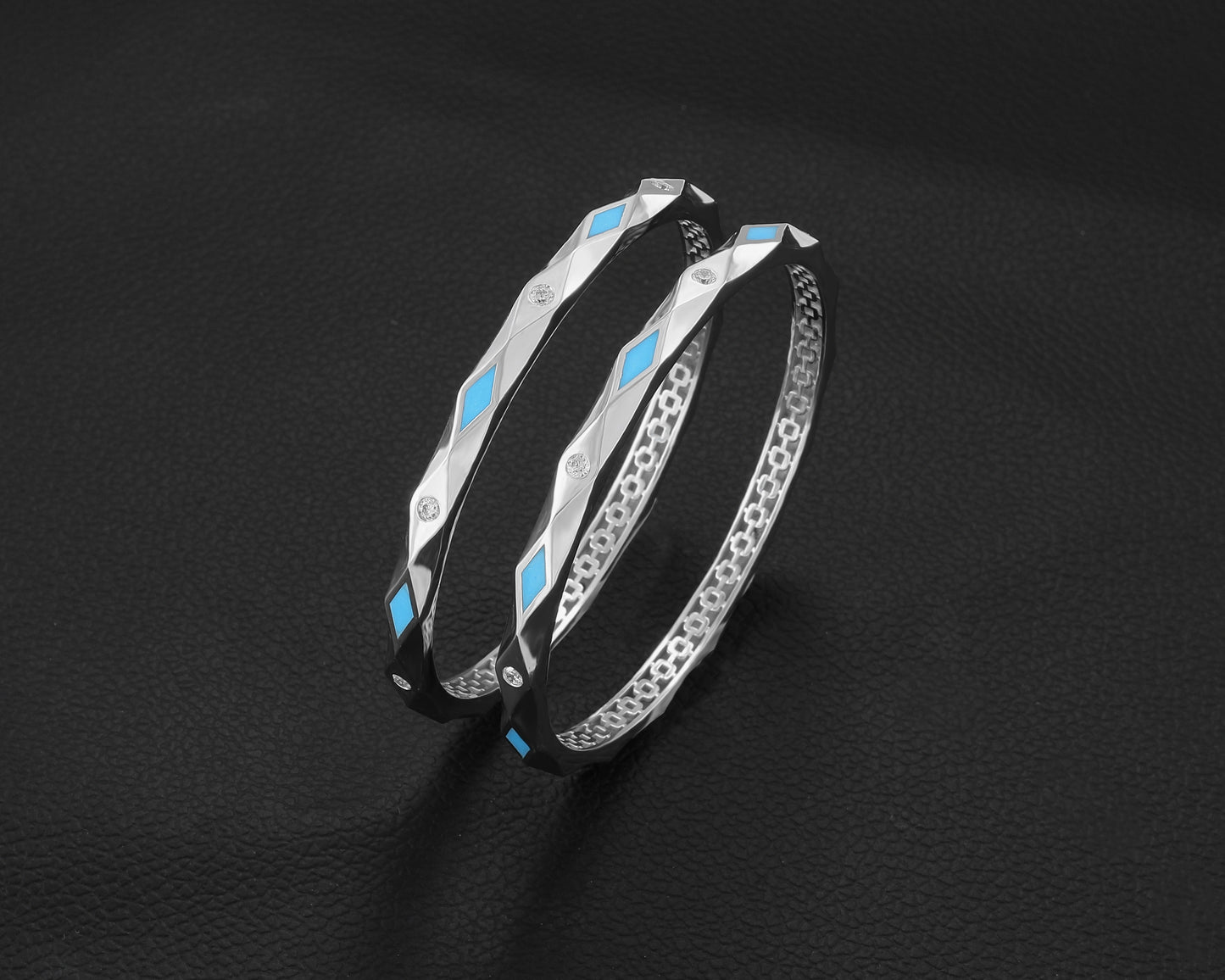 Two silver bracelets with blue accents on a black background