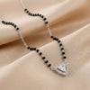 Necklace with black beads and a heart-shaped silver pendant on beige fabric