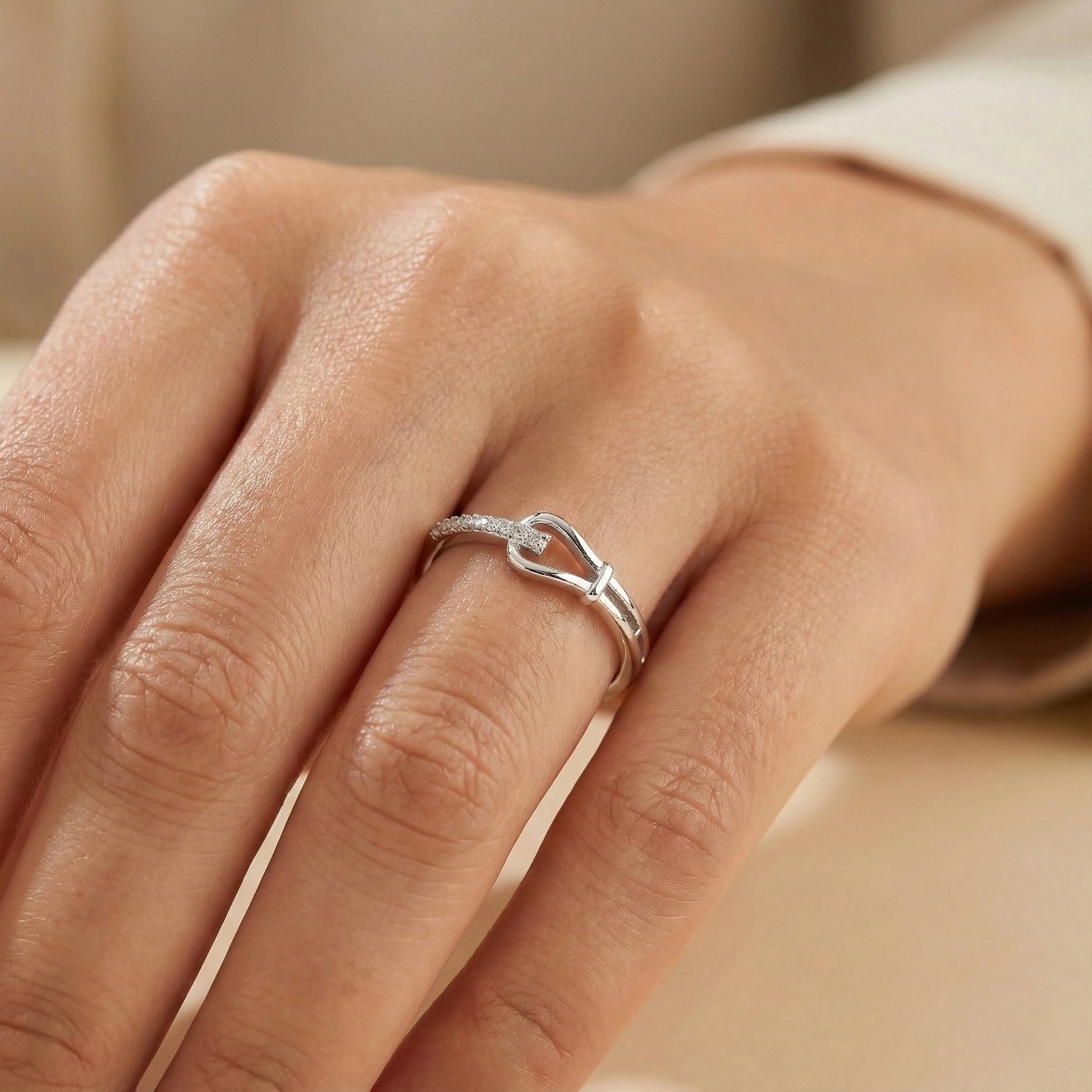 Silver ring on a person's finger with a neutral background