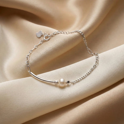 Silver bracelet with a pearl on a beige fabric background