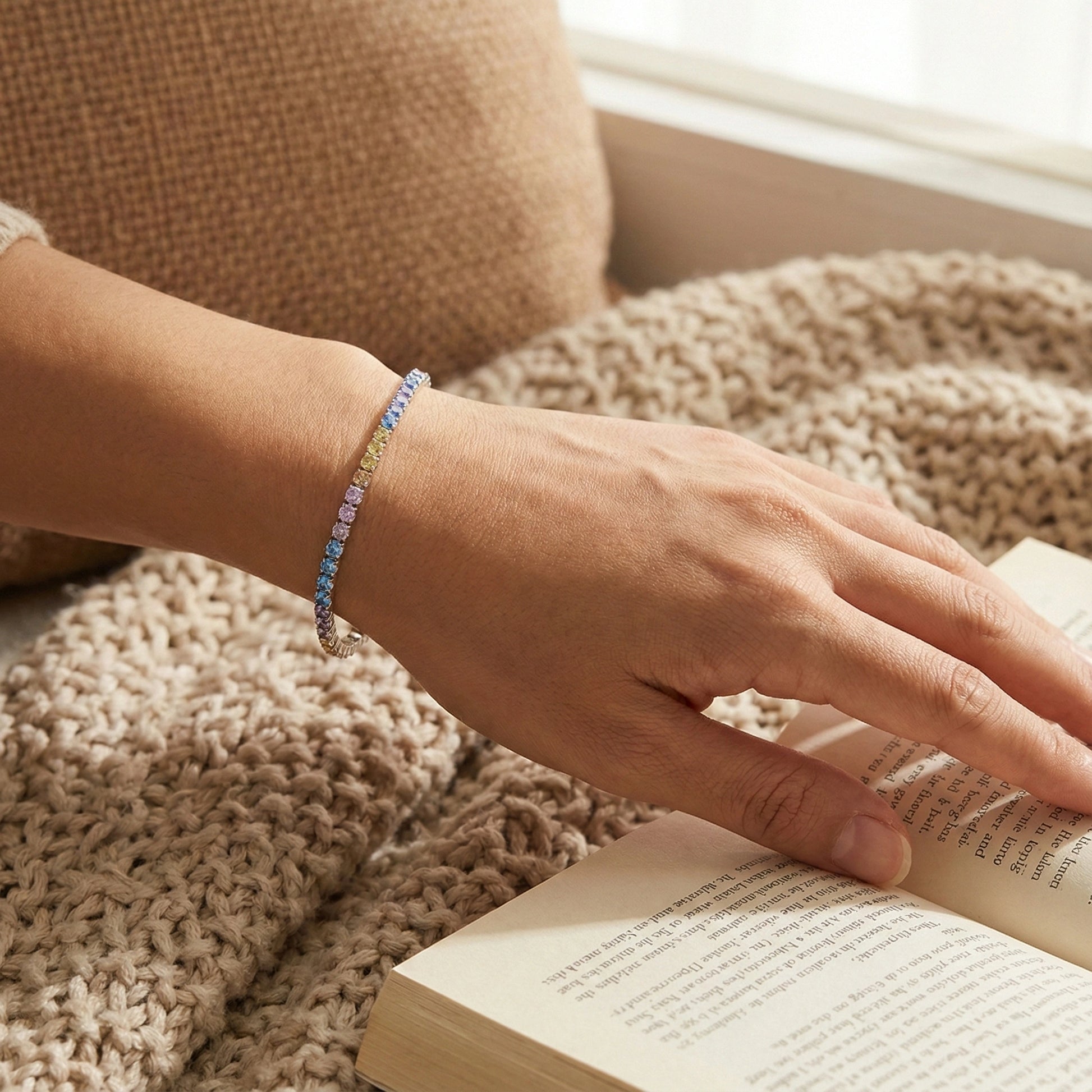 Hand wearing a colorful beaded bracelet on a textured surface with an open book
