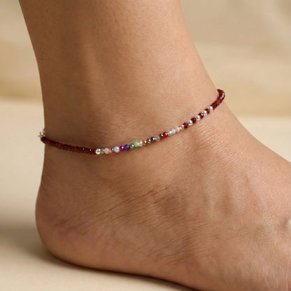 Multicolored beaded anklet on a person's ankle against a neutral background