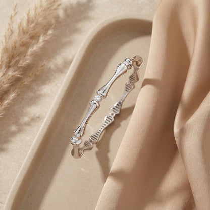 Silver bracelet with bone design on a beige fabric background