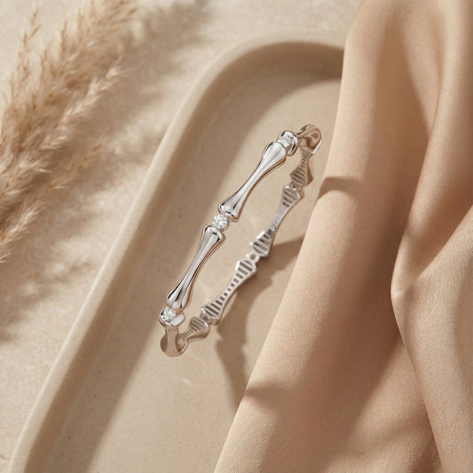 Silver bracelet with bone design on a beige fabric background