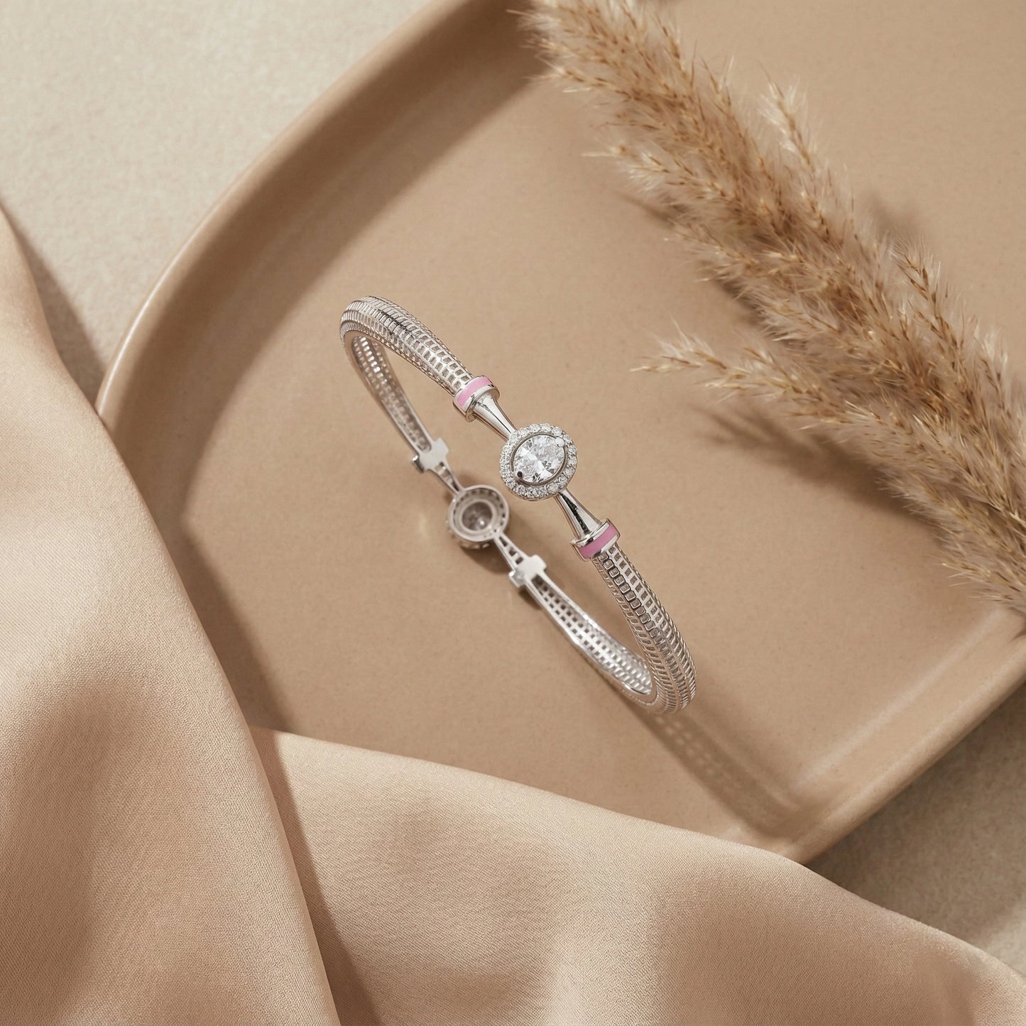 Silver bracelet with pink accents on a beige surface with dried grass