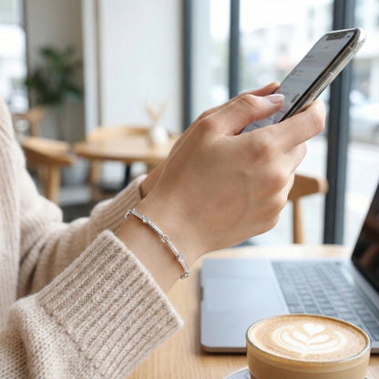 Person using a smartphone with a cup of coffee and laptop in the background